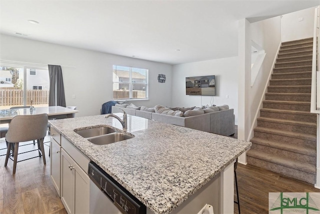 kitchen with sink, dark hardwood / wood-style floors, stainless steel dishwasher, and an island with sink