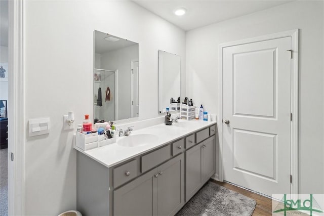 bathroom with hardwood / wood-style flooring, vanity, and walk in shower