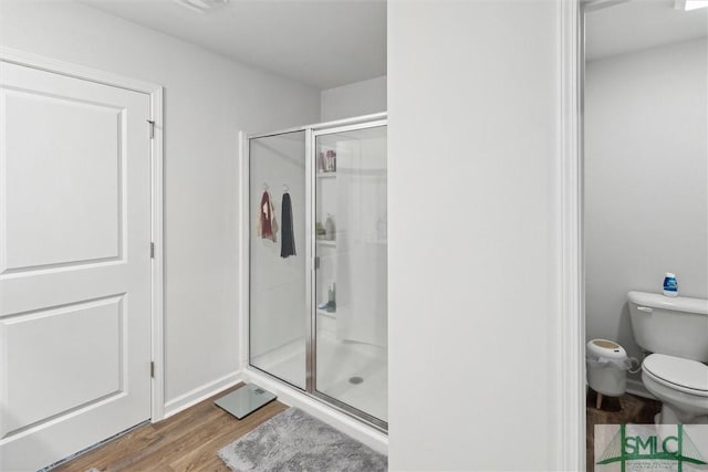 bathroom featuring an enclosed shower, wood-type flooring, and toilet