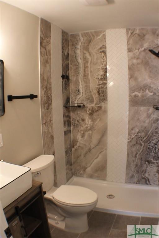 bathroom featuring tile patterned flooring, vanity, tiled shower, and toilet