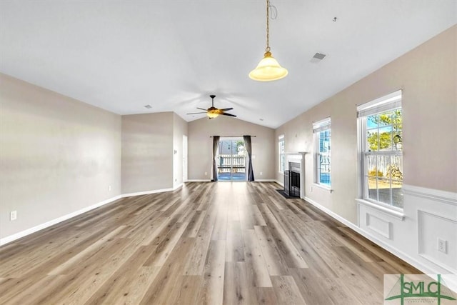 unfurnished living room featuring a ceiling fan, wood finished floors, visible vents, a fireplace, and vaulted ceiling