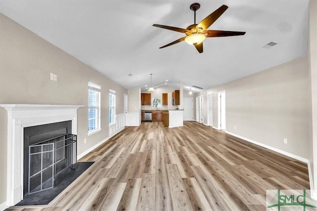 unfurnished living room with light wood finished floors, visible vents, ceiling fan, vaulted ceiling, and a fireplace