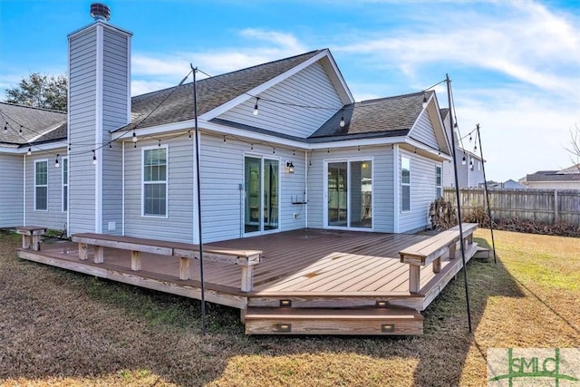 back of property featuring a deck, a yard, fence, and a chimney