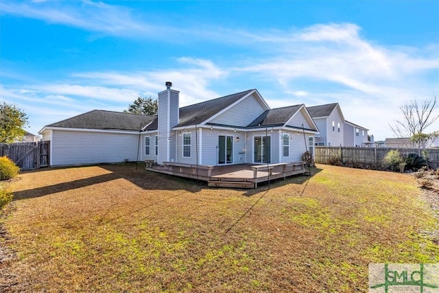 rear view of house with a wooden deck and a lawn