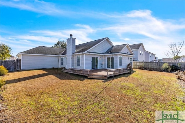rear view of property with a deck, a lawn, a fenced backyard, and a chimney