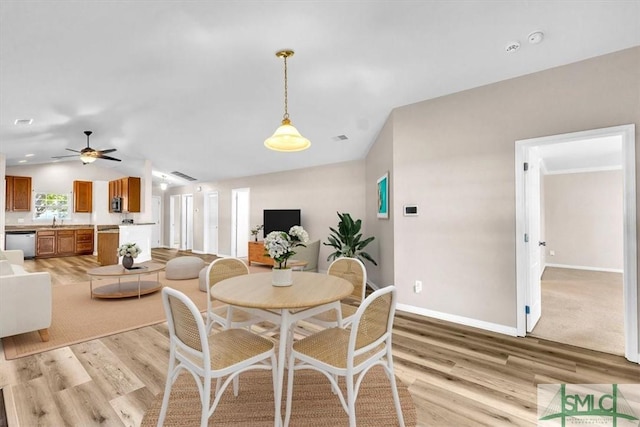 dining area featuring baseboards, lofted ceiling, light wood-style floors, and a ceiling fan