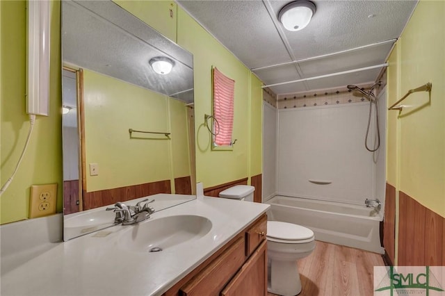 full bathroom with shower / bath combination, wooden walls, vanity, wood-type flooring, and toilet