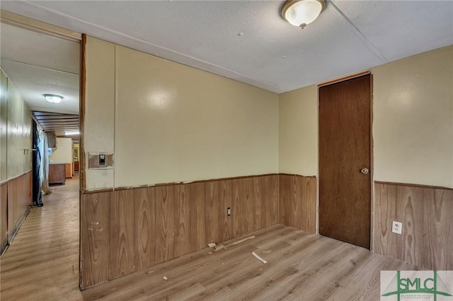 unfurnished room featuring a textured ceiling and light hardwood / wood-style floors