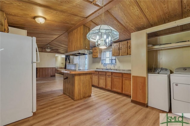 kitchen featuring white fridge, extractor fan, a kitchen island, separate washer and dryer, and wood walls