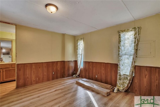 spare room featuring sink, electric panel, and light hardwood / wood-style floors