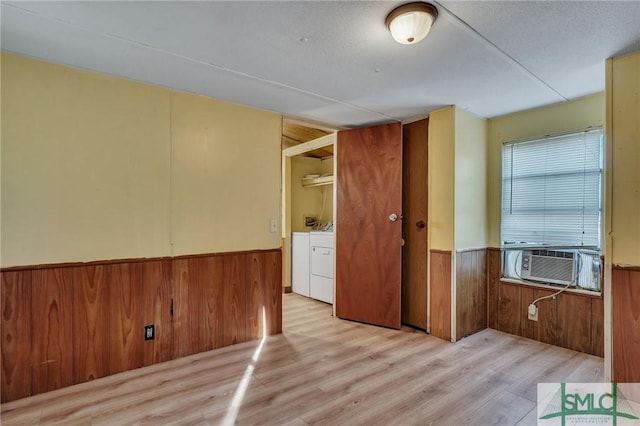 interior space with cooling unit, washer and clothes dryer, and light hardwood / wood-style floors