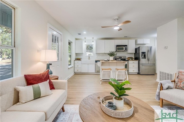 living room with ceiling fan, a healthy amount of sunlight, and light wood-type flooring