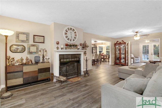 living room featuring hardwood / wood-style flooring, a tile fireplace, a textured ceiling, and french doors