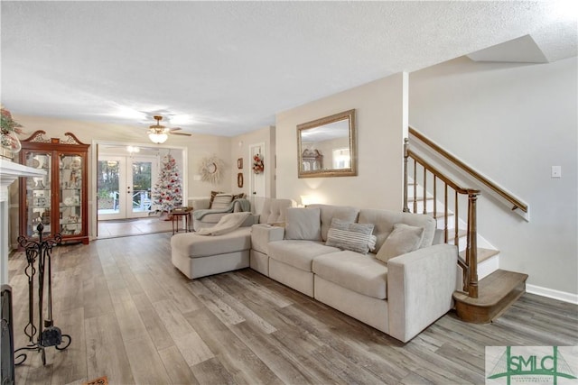 living room featuring french doors, light hardwood / wood-style flooring, and a textured ceiling