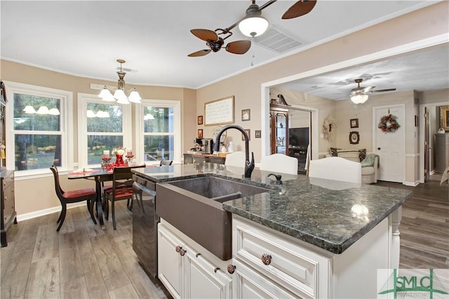 kitchen featuring an island with sink, dishwasher, sink, white cabinets, and light hardwood / wood-style floors