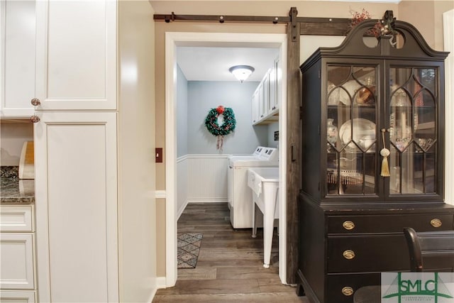 clothes washing area with dark wood-type flooring, cabinets, and washer and dryer