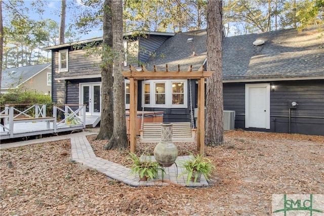 back of house with a wooden deck, a hot tub, a pergola, and french doors