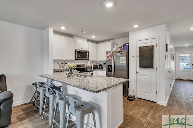 176 Coneflower Rd, Bloomingdale, GA 31302 - kitchen featuring appliances with stainless steel finishes, white cabinetry, a breakfast bar area, kitchen peninsula, and light stone countertops