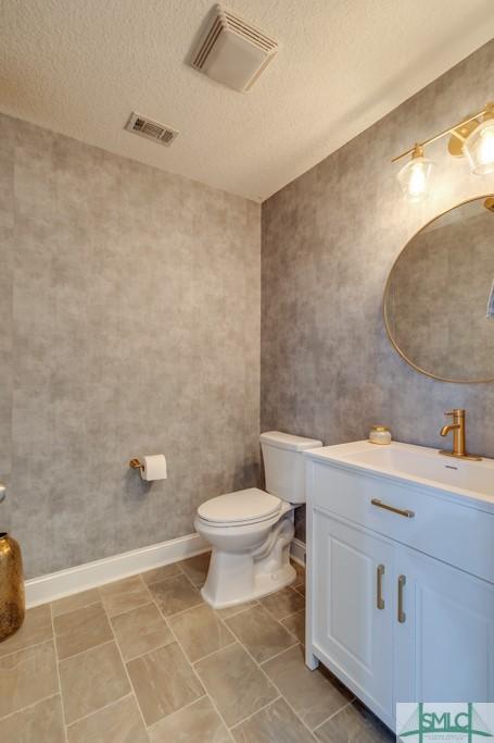 bathroom with vanity, toilet, and a textured ceiling