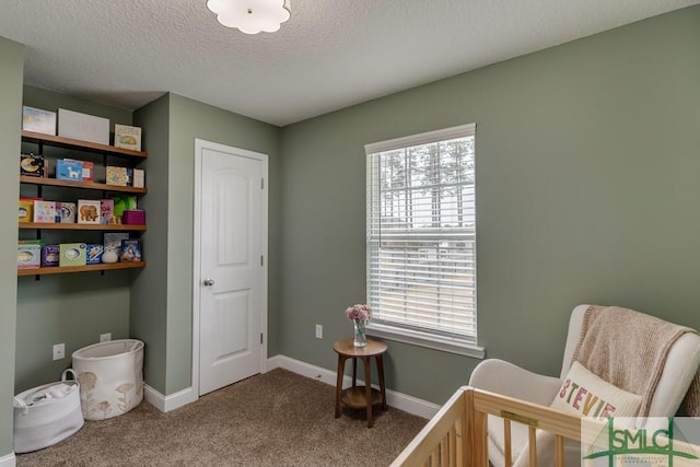 bedroom featuring a nursery area, carpet floors, and a textured ceiling