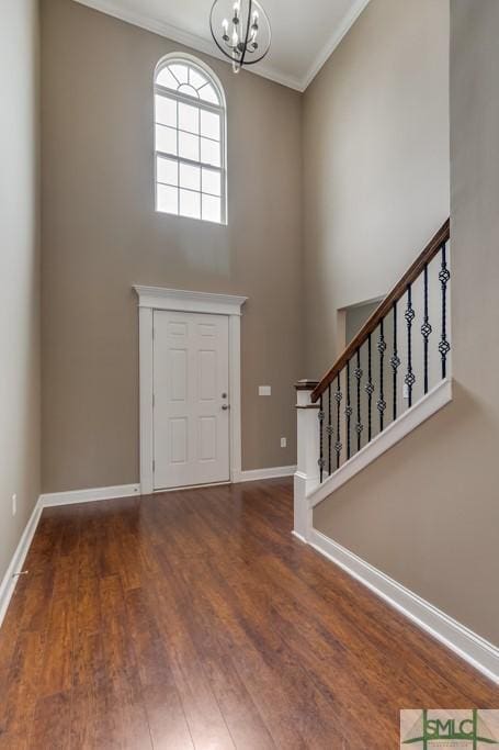 foyer entrance with ornamental molding, dark hardwood / wood-style flooring, and an inviting chandelier