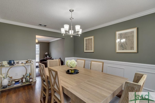 dining area with ornamental molding, dark hardwood / wood-style flooring, a textured ceiling, and a notable chandelier