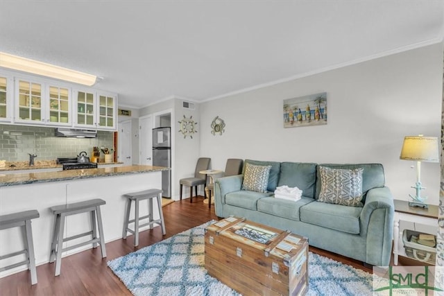 living area with crown molding, visible vents, and dark wood finished floors