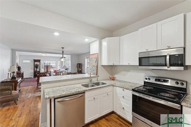 kitchen with sink, stainless steel appliances, kitchen peninsula, and white cabinets