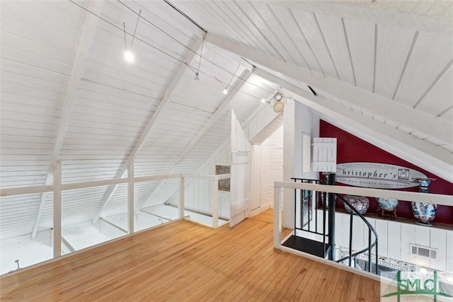 bonus room featuring wood-type flooring and vaulted ceiling with beams