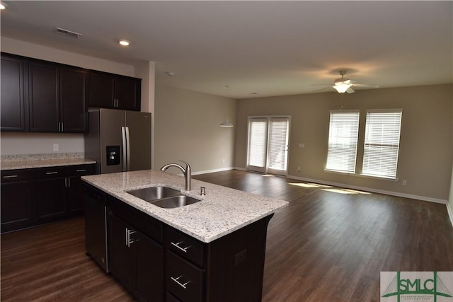 kitchen with dark hardwood / wood-style floors, sink, stainless steel fridge with ice dispenser, and a center island with sink