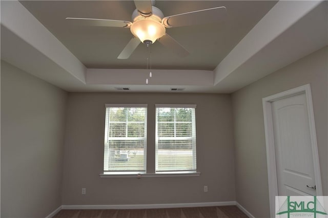 empty room featuring a raised ceiling and ceiling fan