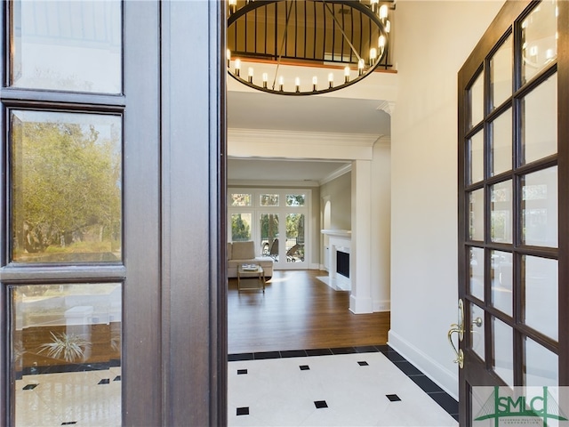 tiled foyer featuring crown molding and a notable chandelier