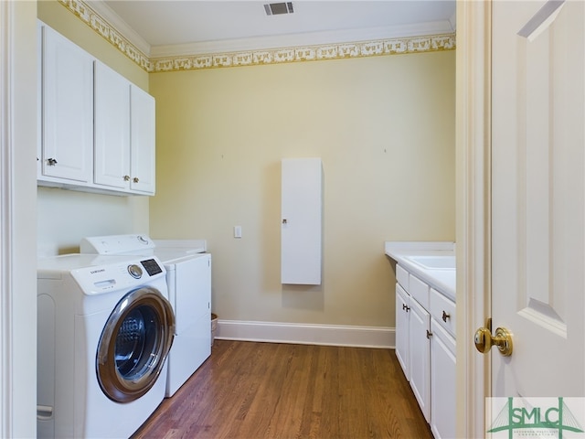 laundry area featuring dark hardwood / wood-style floors, ornamental molding, cabinets, and washing machine and clothes dryer