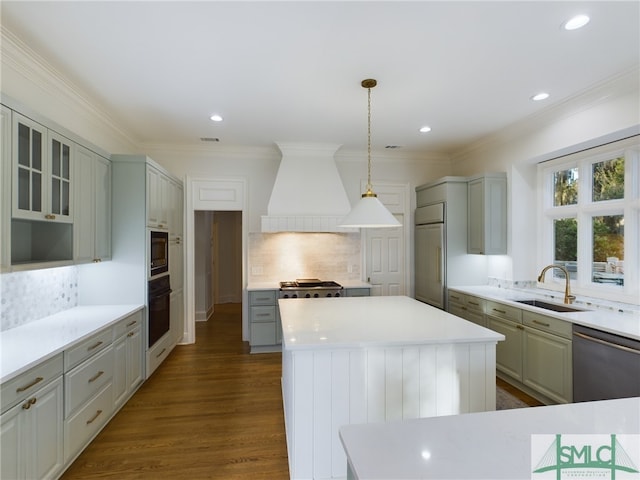 kitchen with sink, custom exhaust hood, built in appliances, gray cabinets, and a kitchen island