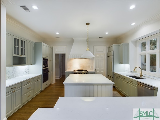 kitchen featuring sink, built in appliances, custom range hood, a kitchen island, and pendant lighting