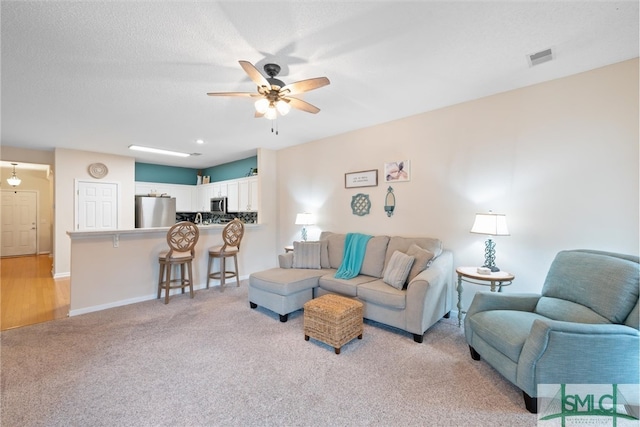 living room with light carpet, a textured ceiling, and ceiling fan