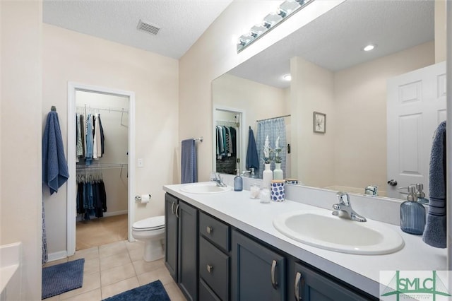 bathroom featuring vanity, tile patterned floors, a textured ceiling, and toilet