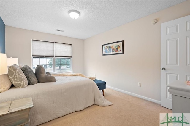 bedroom with light colored carpet and a textured ceiling