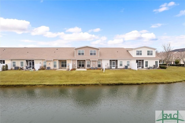 back of house with a lawn, central air condition unit, and a water view