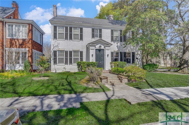 colonial-style house featuring brick siding and a front lawn