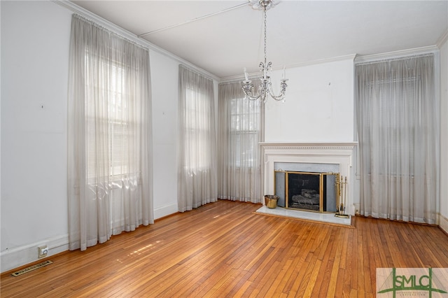 unfurnished living room featuring a wealth of natural light, visible vents, a fireplace with raised hearth, and wood-type flooring