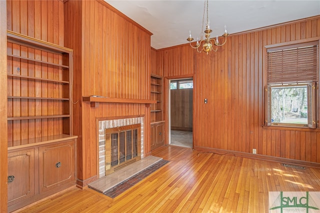 unfurnished living room with wooden walls, a healthy amount of sunlight, and hardwood / wood-style flooring