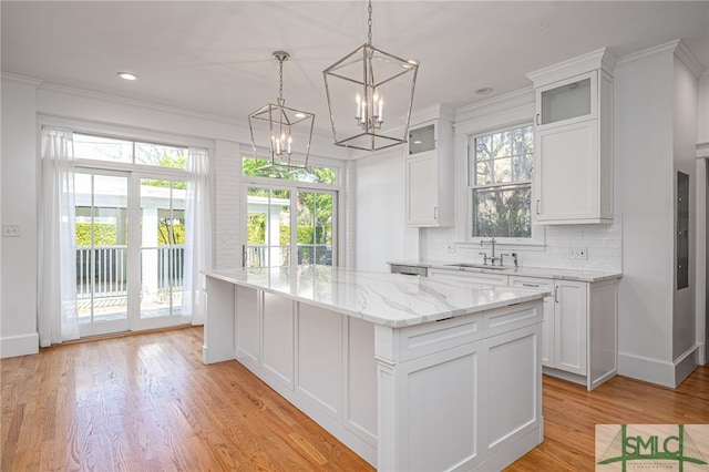 kitchen with a sink, decorative backsplash, light wood-type flooring, and a center island