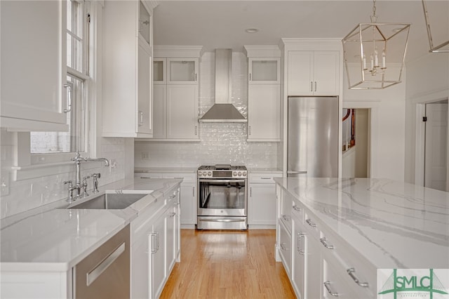 kitchen with white cabinetry, stainless steel appliances, wall chimney exhaust hood, and a sink