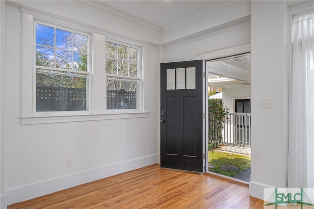 entryway featuring light wood-style flooring, crown molding, and baseboards