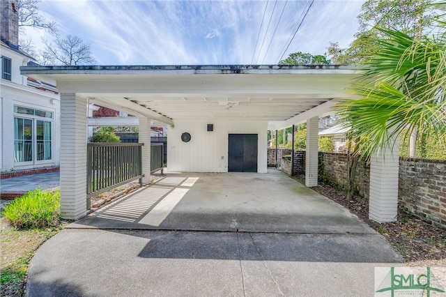 view of parking featuring a carport, concrete driveway, and fence