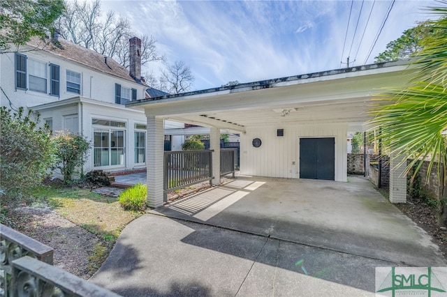 view of parking with a carport and fence