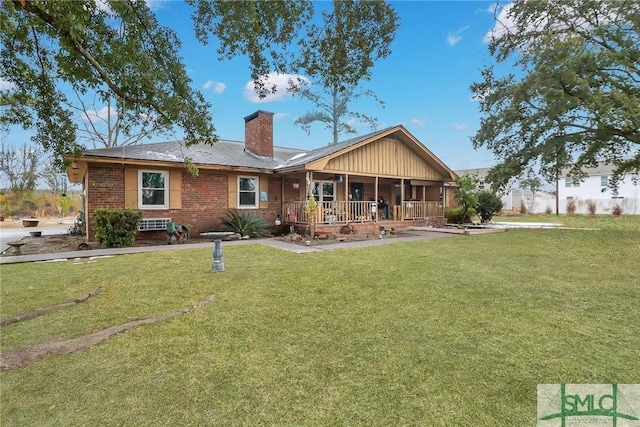 rear view of property featuring covered porch and a lawn