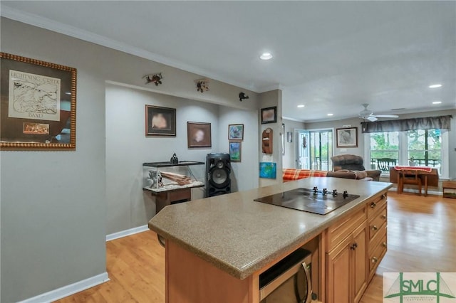 kitchen with a kitchen island, black electric cooktop, ceiling fan, crown molding, and light wood-type flooring