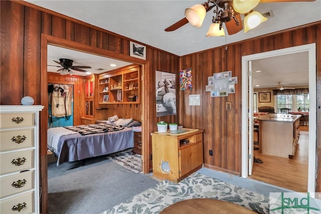 bedroom featuring ceiling fan and wood walls